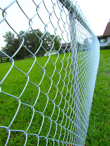 Galvanized chain link fencing with knuckle ends with house in background corner